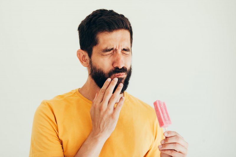 man wincing from tooth sensitivity